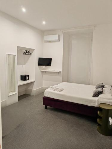 a white bedroom with a bed and a television at Art Street Hotel in Naples