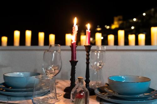 a table with two candles and two bowls and wine glasses at Tahona Ático - Gaiamoment in Alcalá del Júcar