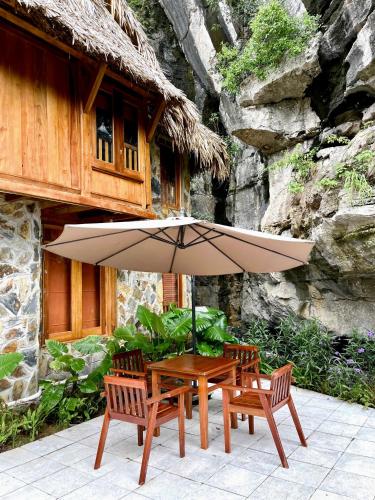 a table and two chairs and an umbrella at Hang Mua Ecolodge in Ninh Binh
