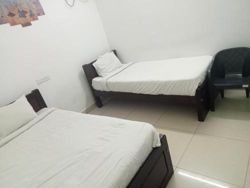 a room with two beds and a chair in it at La township stay in Puducherry