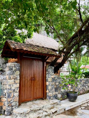 a building with a wooden door and a stone wall at Hang Mua Ecolodge in Ninh Binh