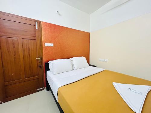 a small bedroom with a bed and a wooden door at Vaisharad Homestay Trivandrum in Trivandrum