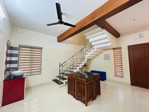 a living room with a staircase and a ceiling fan at Vaisharad Homestay Trivandrum in Trivandrum