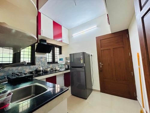 a kitchen with a sink and a refrigerator at Vaisharad Homestay Trivandrum in Trivandrum