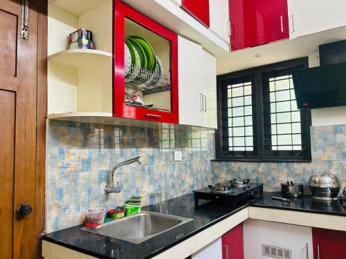 a kitchen with a sink and a red cabinet at Vaisharad Homestay Trivandrum in Trivandrum