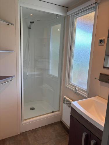 La salle de bains est pourvue d'une douche en verre et d'une fenêtre. dans l'établissement Le Camping de Ripan, à Bessenay