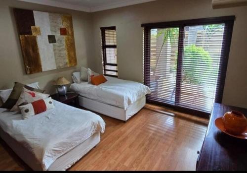 a bedroom with two beds and a large window at Pecanwood Estate Dream views 4 bedroom Villa with pool in Hartbeespoort