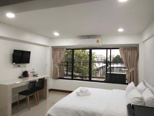 a bedroom with a bed and a desk and a window at Money Home in Bangkok
