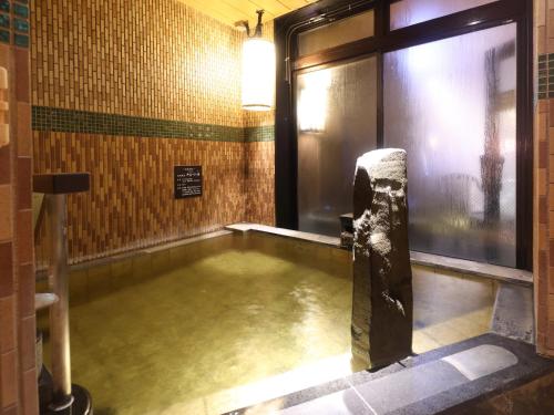 a bath room with a pool of water in the floor at Dormy Inn Kitami in Kitami