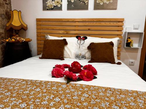 a bed with a bunch of red roses on it at Casa da Vila - Apartamento rés chão in Alpedrinha