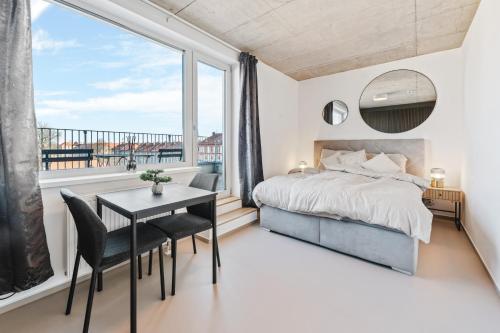 a bedroom with a bed and a table with chairs and a large window at Apartmány Gočárova třída in Hradec Králové