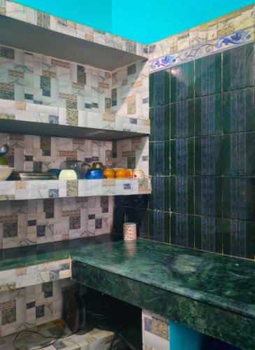 a kitchen with a green counter top and tiles at Risabya Guest House in Gājol