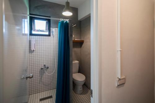 a bathroom with a toilet and a shower with a blue shower curtain at Dongshan Yi Hostel in Dongshan