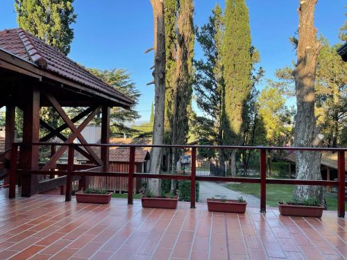 a wooden gazebo on a patio with trees at Hotel Samay Huasi in Villa General Belgrano