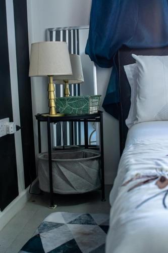 a table with a lamp on it next to a bed at Ngwanuuza Lifestyle Apartments in Gaborone