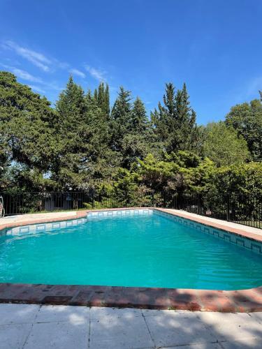 a swimming pool with blue water in front of trees at Hotel Samay Huasi in Villa General Belgrano