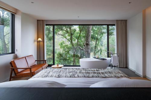 a bedroom with a tub and a chair and a large window at 至也 黄果树 in Xinggong