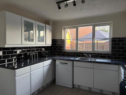 une cuisine avec des armoires blanches et des comptoirs noirs dans l'établissement Theos Nook 4 Bedroom House, Sleeps 6, à Hopton on Sea