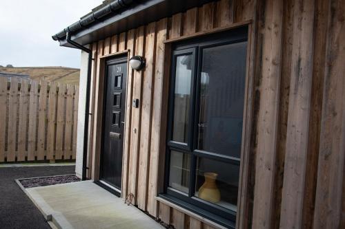 a wooden house with a window and a door at Coorie Voe in Stromness