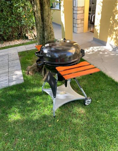 a grill sitting on a cart in the grass at Villa Lori Apartments Garden and Beach in Peschiera del Garda