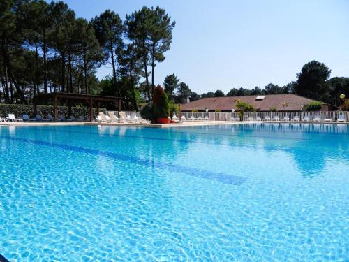une grande piscine d'eau bleue avec des chaises blanches dans l'établissement Maison climatisée proche Arcachon, à Gujan-Mestras