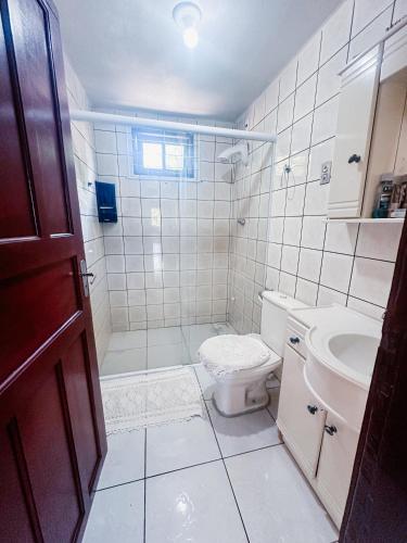 a white bathroom with a toilet and a sink at Sítio Rota 77 in Canelinha