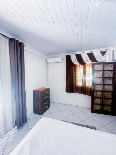 a bedroom with a bed and a dresser and a window at Sítio Rota 77 in Canelinha