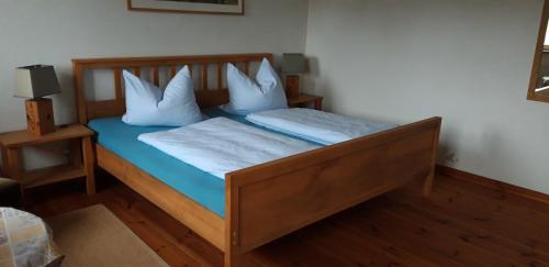a bedroom with a wooden bed with white pillows at 160 qm große Ferienwohnung für 5 Personen nahe Stettiner Haff in Bugewitz