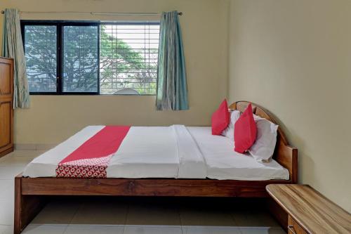 a bedroom with a bed with red pillows and a window at Hotel O Green Hills Resort in Sopāra