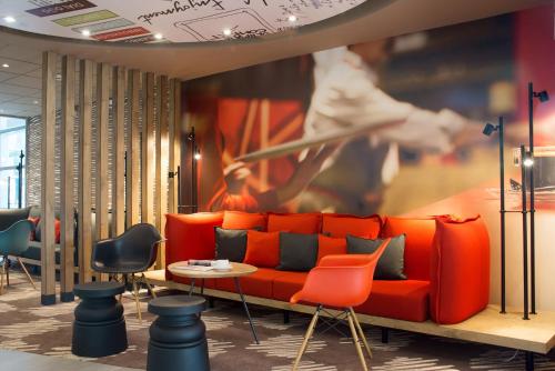 a living room with an orange couch and a painting at Ibis Poznan Stare Miasto in Poznań