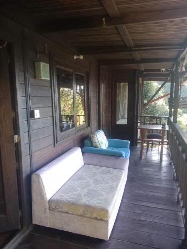 a porch of a house with a couch and windows at Sukoon Nature Retreat Near Bhatrojkhan Ranikhet in Tota Ām