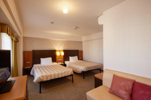 a hotel room with two beds and a couch at GRG Hotel Naha Higashimachi in Naha