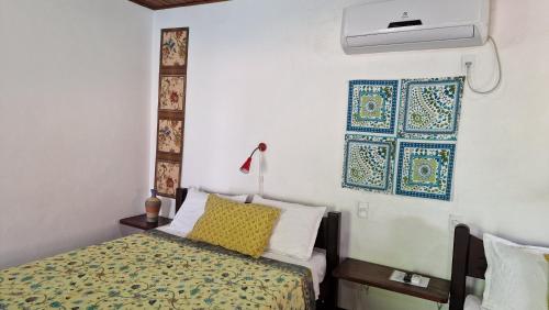 a bedroom with a bed and a wall with a fan at Pousada Casa da Edinha in Ilha de Boipeba