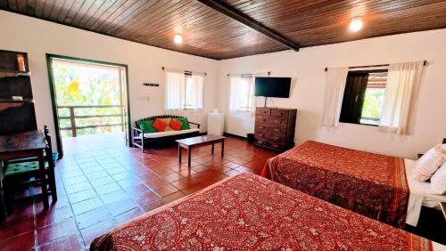 a hotel room with two beds and a living room at Pousada Casa da Edinha in Ilha de Boipeba