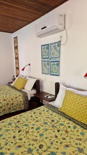 a hotel room with two beds and a table at Pousada Casa da Edinha in Ilha de Boipeba