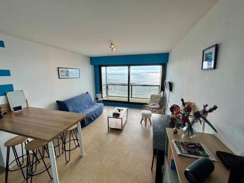 un salon avec un canapé bleu et une table dans l'établissement Vue Mer Exceptionnelle - 2 Étoiles, à Les Sables-dʼOlonne