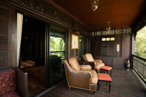 a porch with chairs and a table on a house at Akara House Sukhothai - Luxury Riverside Residence in Sukhothai