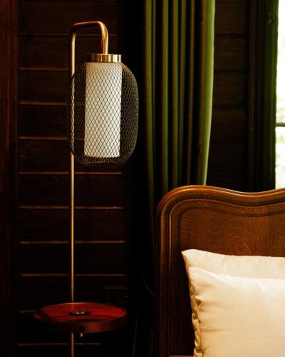 a lamp on a side table next to a bed at Akara House Sukhothai - Luxury Riverside Residence in Sukhothai