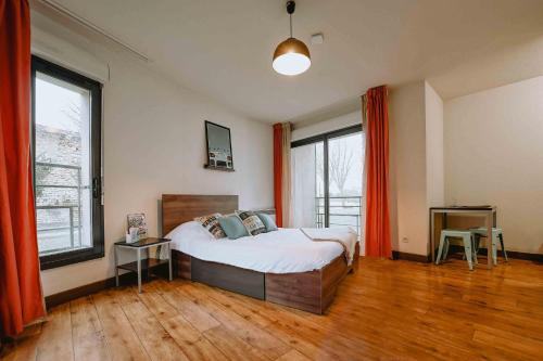 a bedroom with a large bed with orange curtains at Zenao Appart Hôtel Nevers Quai de Loire in Nevers