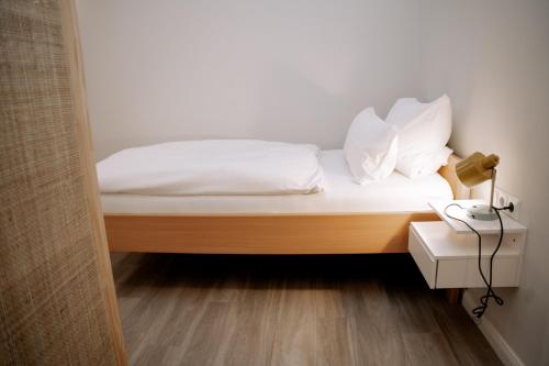 a bed with white sheets and pillows and a telephone at Hotel Seehof Norderney OHG in Norderney