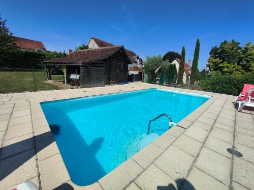 une piscine dans une cour avec une maison dans l'établissement Les gîtes du Zoo,2 logements 10min du zoo piscine partagée juin-octobre & spa partagée avril-octobre ,calme & reposant, à Châteauvieux