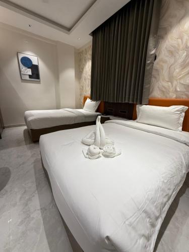 a hotel room with two beds and two cups on a bed at Hotel Aishwarya in Akalkot
