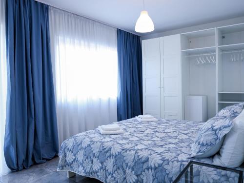 a bedroom with a bed and a window with blue curtains at Golden Gate 21 in Ruma
