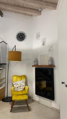 a yellow chair in a living room with a fireplace at Casa Cibella Authentic Charme Apartments in Agrigento