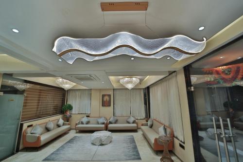a living room with couches and a ceiling at Hotel Aishwarya in Akalkot