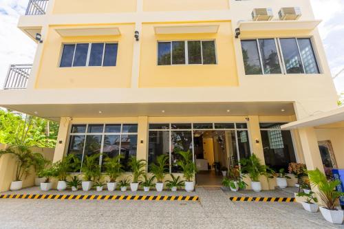 a yellow building with plants in front of it at Anahaw Seaside Inn in Bantayan Island