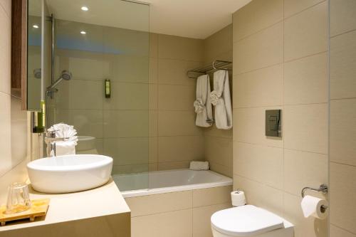 a bathroom with a sink and a toilet and a tub at Melpo Antia Hotel & Suites in Ayia Napa
