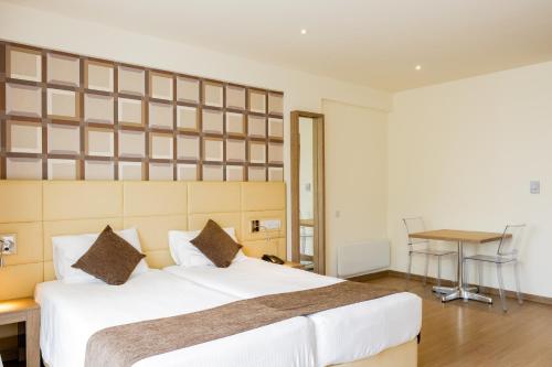 a bedroom with a large white bed and a table at Melpo Antia Hotel & Suites in Ayia Napa