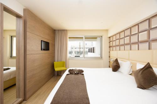 a bedroom with a large bed and a yellow chair at Melpo Antia Hotel & Suites in Ayia Napa