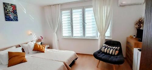 a bedroom with a bed and a chair and a window at Къща за гости Веселина - Ивайловград in Ivaylovgrad
